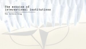 A high-key, minimalist image featuring a row of sharp, bullet-like white shapes pointing downward toward a faded, translucent NATO compass rose. The text "The erosion of international institutions" is written in a black typewriter font in the upper left corner, underscored by the words "The Bethics Blog."